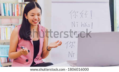 Asian woman teacher teaching remotely at home office with online technology laptop.Teaching Chinese language for Students at home school.Translation on paper text 