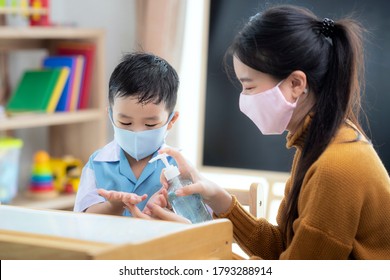Asian Woman Teacher Use Alcohol Gel On Hand Of Her Student For Prevent Virus From Covid19 In Classroom In Preschool.
