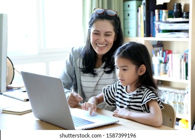 The Asian Woman Teaching Her Child To Use Computer.