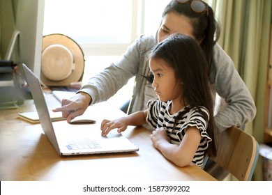 The Asian Woman Teaching Her Child To Use Computer.