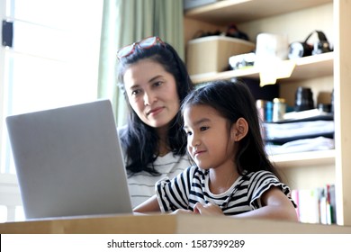 The Asian Woman Teaching Her Child To Use Computer.