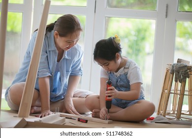 Asian Woman Teaching Her Daughter Assembling New DIY Furniture At Home