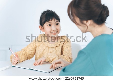 Asian woman teaching little girl. Mother and daughter. Cram school. Tutor.