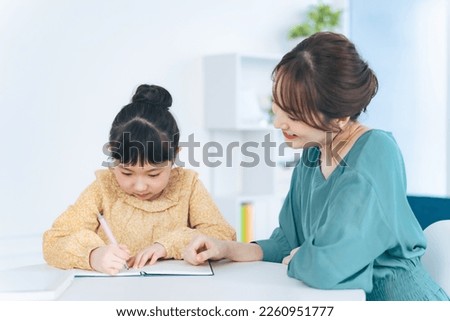 Asian woman teaching little girl. Mother and daughter. Cram school. Tutor.