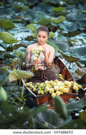 Asian woman in Thai rural traditional dress sitting on boat in the lotus garden at morning