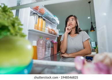 Asian Woman Thinking While Open The Refrigerator Door Before Cooking