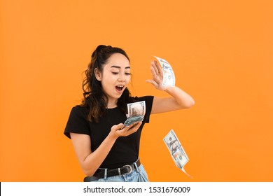 Asian woman throwing money against color background