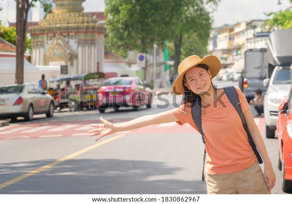 Asian woman, a\
tourist people hailing a taxi or a cab, travelling or waving a hand\
on street road in Bangkok City, Thailand in holiday vacation.\
Lifestyle activity\
concept.