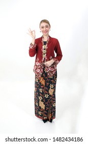 Asian woman traditional red maroon kebaya sharong on white background showing ok finger sign 