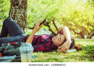 Asian woman travel nature. Travel relax. sleep See Mobile Phone On the lawn in the park. in summer. - Shutterstock ID 1100868512