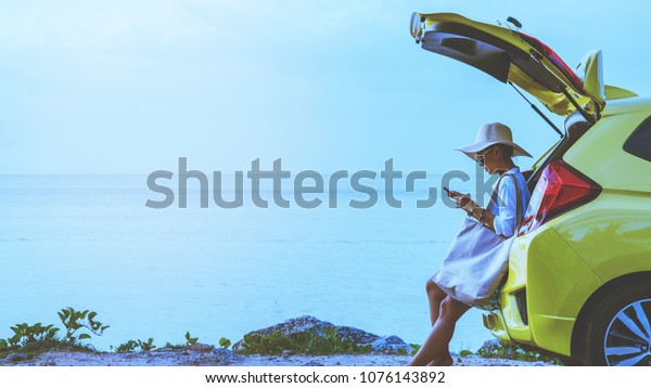 Asian woman travel nature. Travel relax. Sitting\
on the car at the beach.