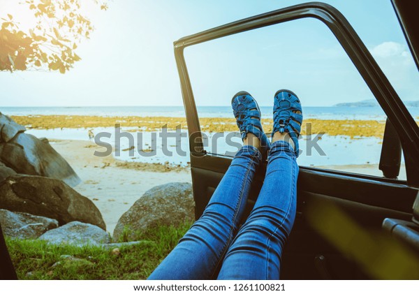 Asian woman travel nature. Travel relax at the beach\
in the summer. Sitting in the car Happy to see the sea and Leg\
outside the car.
