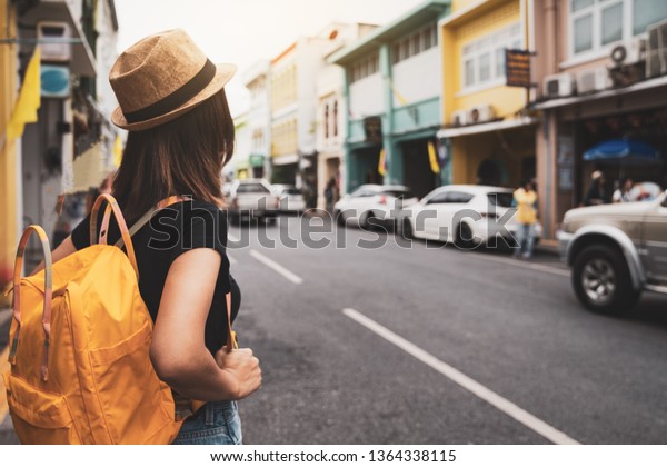 Asian woman traveler backpack city concept,\
Tourist is walking on the street, Young asian traveling backpacker\
in phuket old town,\
Thailand