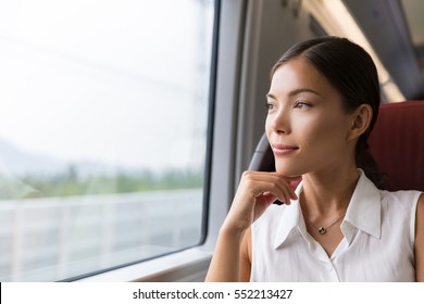 Asian woman traveler contemplating outdoor view from window of train. Young lady on commute travel to work sitting in bus or train. - Powered by Shutterstock