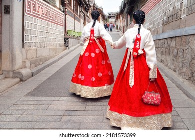 Asian Woman Traveler In Traditional Korean Dress Or Hanbok Dress Walking In Old Palace With Sakura Flower Background, Seoul City, South Korea