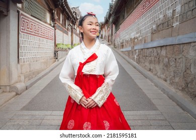 Asian Woman Traveler In Traditional Korean Dress Or Hanbok Dress Walking In Old Palace With Sakura Flower Background, Seoul City, South Korea