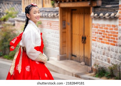 Asian Woman Traveler In Traditional Korean Dress Or Hanbok Dress Walking In Old Palace With Sakura Flower Background, Seoul City, South Korea