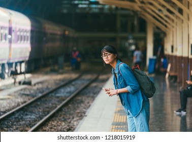 Asian woman traveler waiting train on the platform of the railway station- travel and transportation concept