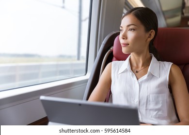 Asian woman traveling using laptop in train. Businesswoman pensive looking out the window while working on computer on travel commute to work. - Powered by Shutterstock