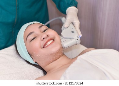 An Asian Woman Undergoes A HIFU Procedure On Her Jawline. A Cosmetic Treatment For Skin Tightening.