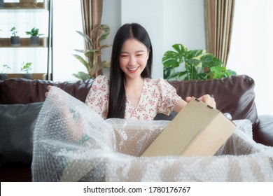 Asian Woman Unpack Packaging After Online Shopping From Discount Store, This Image Can Use For Business, Post, Ecommerce And Delivery Concept