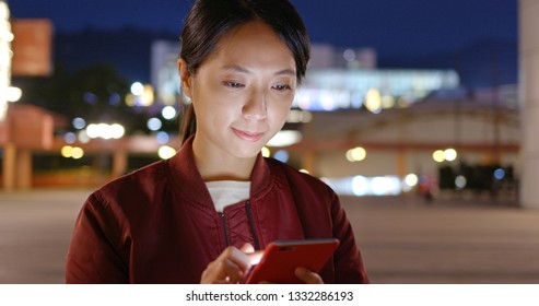 Asian woman use of mobile phone in city at night