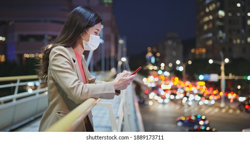 asian woman use smartphone outdoor with face mask while commuting in the city