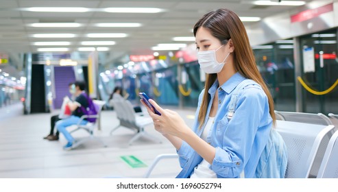 Asian woman use a smartphone with surgical mask face protection and keep social distancing while waiting in the metro or train station - Powered by Shutterstock