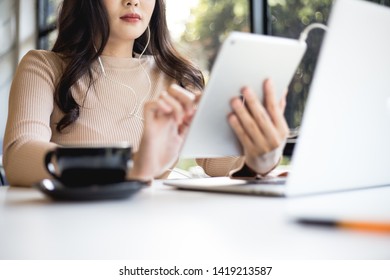 Asian woman use tablets while listening to music in cafe.