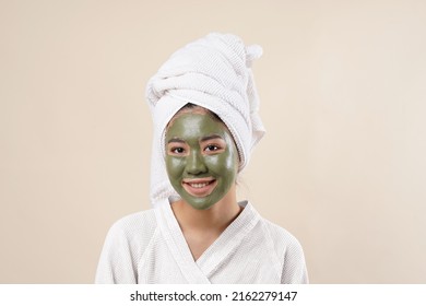 An Asian Woman Using Bathrobe, Towel In Her Hair, And Face Mask, Taking Selfie And Pose To The Camera. Isolated On Cream Background.