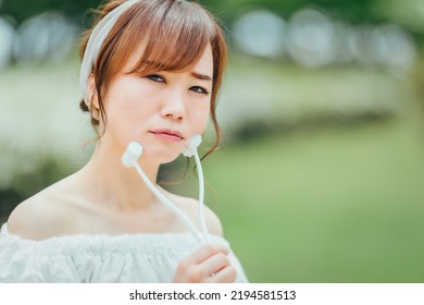 Asian Woman Using Facial Roller In Green