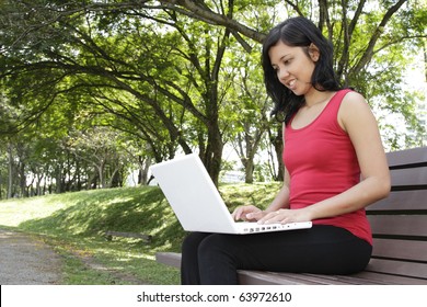 An Asian Woman Using Her Laptop At A Park