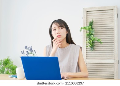 Asian woman using the laptop
 at home - Shutterstock ID 2110388237
