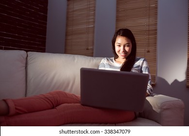 Asian Woman Using Laptop At Night At Home In The Living Room