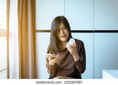 Asian Woman Using Mobile Phone Searching Information And Reading Medicine Label And Prescription Medications,Health Care And People Concept