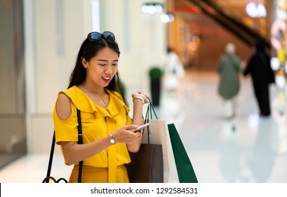 Asian Woman Using Phone In A Shopping Mall
