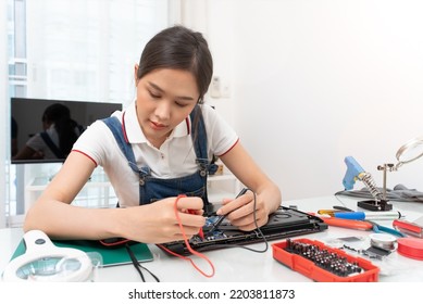 Asian woman using a power meter to check laptop board to repair or replace - Powered by Shutterstock