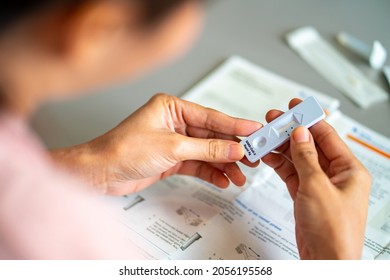 Asian woman using rapid antigen test kit for self test COVID-19 epidemic at home. Confidence female reading user manuals instruction of COVID-19 ATK . Coronavirus pandemic protection concept.