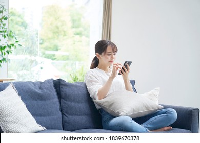 Asian Woman Using The Smart Phone On The Sofa