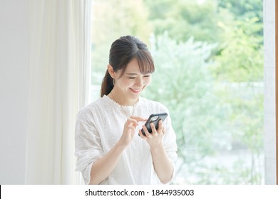 Asian Woman Using The Smart Phone At The Living Room