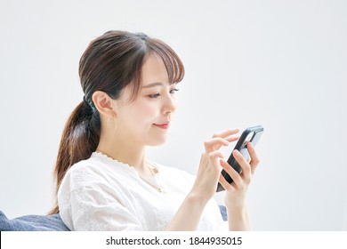 Asian woman using the smart phone on the sofa - Shutterstock ID 1844935015