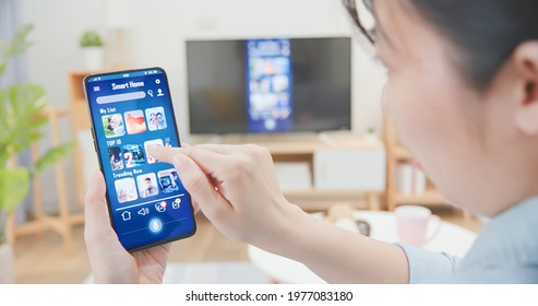 Asian Woman Using Smart Phone To Share Content On Tv In The Living Room At Home - Transfer Video From Smartphone To Television Screen