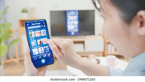 Asian Woman Using Smart Phone To Share Content On Tv In The Living Room At Home - Transfer Video From Smartphone To Television Screen