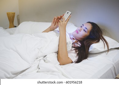 Asian Woman Using Smart Phone At Night On The Bed. Blue Light From Screen Harm The Eyes