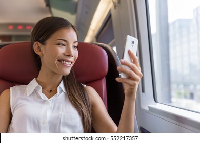 Asian Woman Using Smartphone App Taking Pictures Of The View While Traveling In Train. Happy Young Lady Watching Video Holding Mobile Phone During Transport On Travel Vacation.