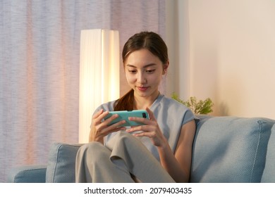 Asian Woman Using The Smartphone At Home At Night