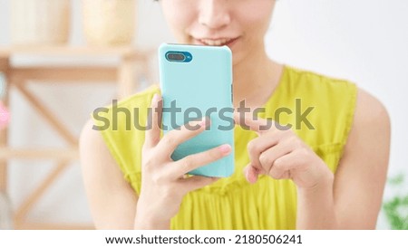 Asian woman using the smartphone at home, no face