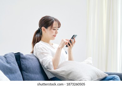 Asian Woman Using The Smartphone On The Sofa
