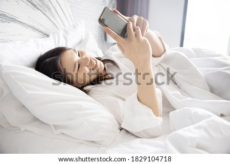 Asian Woman Using Social Media on Mobile Phone While Lying Down in Bed in the Morning