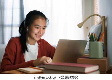 Asian woman video call online via the internet tutor on a computer laptop with headphone, Asia girl is studying while sitting in the bedroom at night. Concept online learning at home  - Shutterstock ID 2018697560